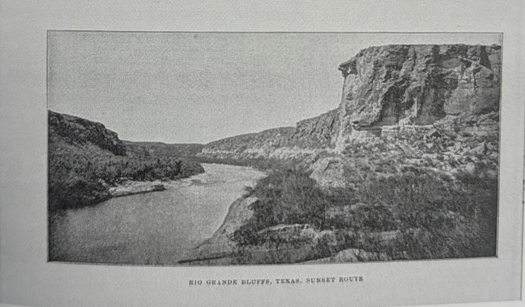 A halftone photograph of a river bending between low scrub-covered banks on the left and a high stratified bluff on the right. Printed beneath the image: RIO GRANDE BLUFFS, TEXAS, SUNSET ROUTE.